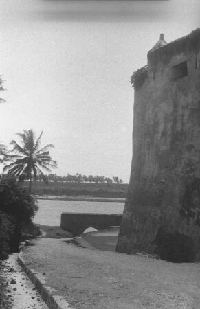 Portugiesisches Fort von Mombasa : Ausschnitt der Architektur der Befestigungsanlage Fort Jesus mit angrenzender Straße und Palme.