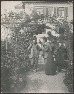Prinz Max von Baden mit seinem Sohn Prinz Berthold auf den Schultern und das Ehepaar Paulcke im Garten von Schloss Kirchberg