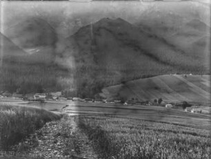 Dorf im Tal : Ein Dorf von Feldern umgeben in einem Tal. Im Hintergrund hohe Berge
