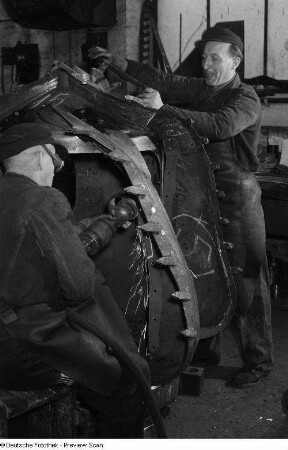 Arbeiter beim Arbeiten mit einem Trennschleifer und Schrauben an einer Maschine