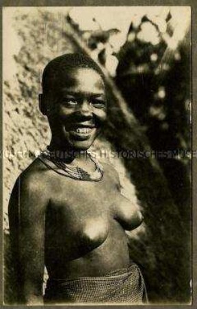 Junge afrikanische Frau vor einer Hütte