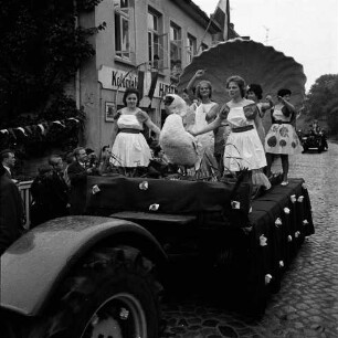 Karpfenfest: Umzug: Matthias-Claudius-Straße / Ahrensböker Straße (hinten): Festwagen, Neptunia, Muschelthron, Nymphen, Schwan, gezogen von Traktor: links Fassade mit Ladenschild "Kolonialwaren", Fahnenschmuck, Wimpelgirlanden: links am Straßenrand und an Fenstern Zuschauer, 8. Oktober 1961