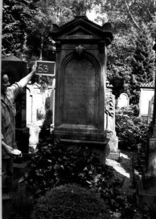 Grabstein 53 (Index: 100109988) Material: Sandstein Zustand: leicht verwittert Maße HxBxT: 240x74x38 cm Beschreibung: Stele, getreppter Sockel, Giebel, Schriftfeld mit Rundbogenabschluß: Grabstein 53