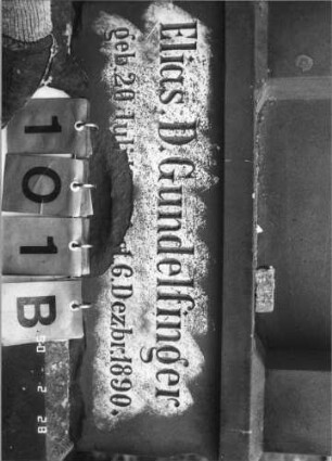 Grabstein 101 (Index: 100114810) Material: Sandstein und ? Zustand: beschädigt im unteren Teil mit kleinem Textverlust, sonst sehr gut Maße HxBxT: 255x66x33 cm Beschreibung: Ädikula, eingezogener Spitzgiebel mit Voluten und Akroter: Grabstein 101B