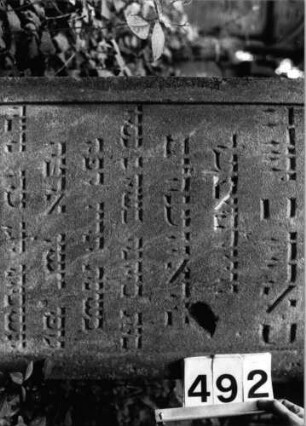 Grabstein 492 (Index: 99803814) Material: Sandstein Zustand: Einschlagloch? Maße HxBxT: 130x57x14 cm Beschreibung: Stele mit verdachtem Rundbogen, profiliertem Rand, Giebelfeld Besonderheit: Endreim: Grabstein 492 (Detailaufnahme)