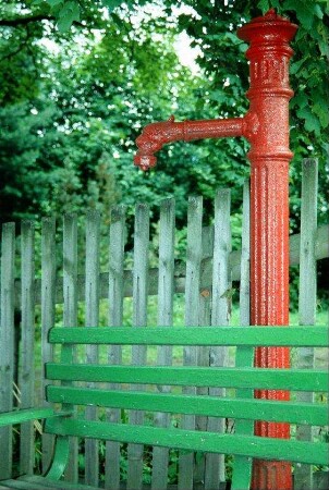 gusseiserne Wasserpumpe hinter einer Bank