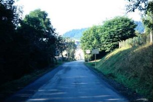 Blick entlang der Straße mit Ortsschild