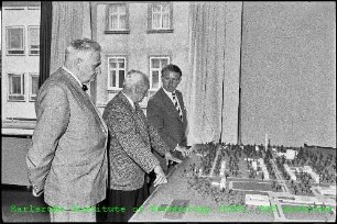 Drei Personen bei der Betrachtung eines Geländemodells des Kernforschungszentrums Karlsruhe (KfK)