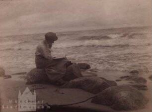 Sellin. Am Meer sitzende, lesende Frau