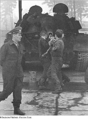 Goldberg (Kreis Lübz). Nationale Volksarmee - Landstreitkräfte. Panzerregiment 8 (PR-8). Freifläche vor Panzerhallen. Zwei Soldaten beim Rohrreinigen der Panzerkanone
