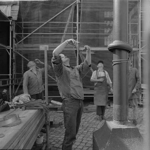 Monteur am Boden gibt Handzeichen an Monteur im Arbeitskorb (Sprechfunk-Einweiser) zum Absetzen des Mastes
