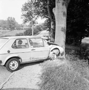 B 75: bei Bad Oldesloe, hinter Forst Kneeden: Verkehrsunfall: Pkw fährt gegen Baum: Unfallwagen quer auf Gehweg, mit eingedrückter Front an Baum: hinten an Straßenrand parkender Pkw: an rechter Straßenseite Straßenbäume, Hecke: an linker Straßenseite Baum, Büsche: hinten Wiesen, Büsche