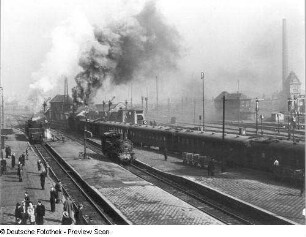 Deutschland. Bahnhof. Blick über Bahnsteige und Gleise mit Dampflokomotiven und Personenzug