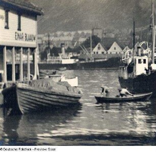 Boote und Frachtkahn an einer Anlegestelle im Hafen gegen die Stadt