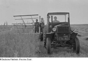Landwirte beim Mähen von Getreide mit Hilfe eines Traktors und einer Mähmaschine