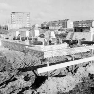 Greifswalder Kehre: Baustelle von Wohngebäuden, dahinter rechts Wohngebäude des Stonsdorfer Weges, links das Rathausgebäude, daneben der Kirchturm des Kirchliches Zentrums am Falkenberg: Blick nach Norden