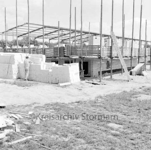 Hamburger Metallbau: Gewerbegebiet: am Hammoorer Weg: Fertigungsbetrieb für Wäschereimaschinen: Werkhalle in Bau: Rohbau mit Gerüst, Arbeiter an Stapel von Mauersteinen, Baumaterialien