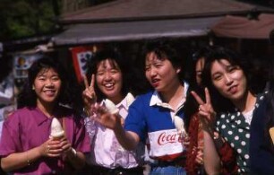 Tokio. Lachende Studentinnen einer Straße, das bei jungen Leuten landesweit übliche Victory-Zeichen für das Foto machend
