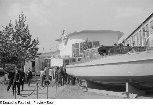 Messebesucher vor dem Ausstellungsgebäude der IFA (Industrieverband Fahrzeugbau), im Vordergrund ein Motorboot
