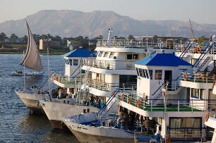 Luxor - Schiffe am Nilufer : Ägyptische Nil-Kreuzfahrtschiffe und eines der traditionellen Segelboote auf dem Nil, Blick zu den Bergen von Theben-West, aufgenommen 2006 in Luxor