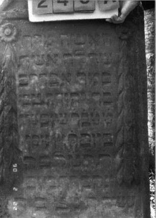 Grabstein 246 (Index: 100115984) Material: Sandstein Zustand: verwittert Maße HxBxT: 116x68x13 cm Beschreibung: Stele mit konkav eingezogenem Segmentbogenabschluß, eingetieftes Schriftfeld Symbolik: Blüten, Ranken: Grabstein 246A