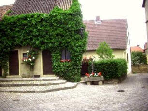 Kirchhof im Nordwesten-Nordteil mit verändertem Gaden (Gründung 13-14 Jh - im 19 Jh zu Wohnzwecken umgebaut) sowie Durchbruch in der Kirchhofmauer zum Ort