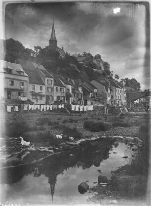 Saarburg : Saarburg. Wohnhäuser am linken Saarufer vor der Saarbücke, darüber der Burgberg mit der Ruine der Burg. Ansicht von Süden