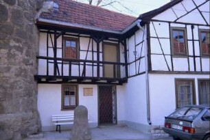 kleines Wohnhaus mit Fachwerkobergeschoss am Fuß eines Stadtmauerturms