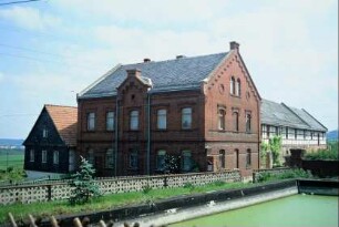 Backsteinbau, davor Teich