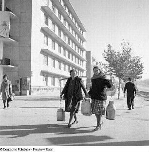 Wasserträgerinnen vor modernem Gebäude