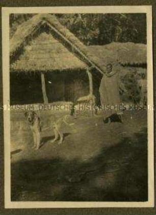 Afrikaner mit Hund vor einer Hütte