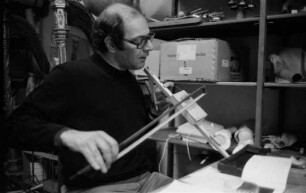 Köln. Mauricio Kagel in seinem Archiv, eines seiner selbstgebauten Streichinstrumente spielend