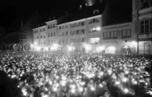 Freiburg: Menschenmenge mit Kerzen, mit Häuserfront am Münster