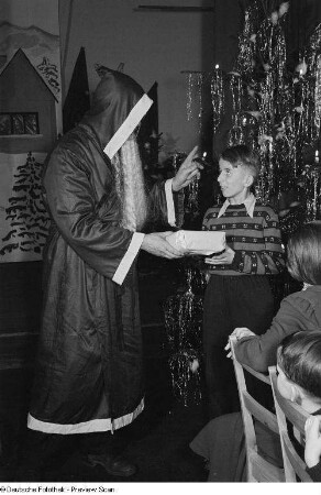 Weihnachtsmann beim Überreichen von Geschenken an Kinder auf der Weihnachtsfeier des VEB Kartographie