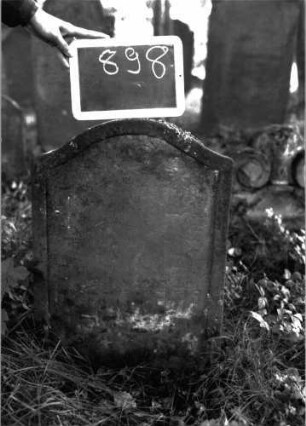 Grabstein 898 (Index: 100103751) Material: Sandstein Zustand: völlig verwittert Maße HxBxT: 65x45x7 cm Beschreibung: Stele, Konvexbogenabschluss, Schriftfeld eingetieft: Grabstein 898