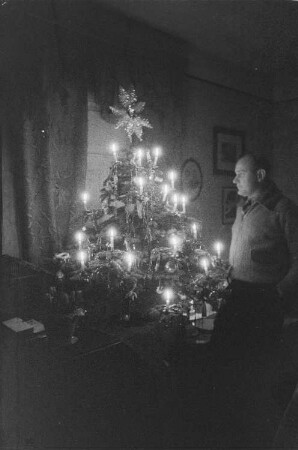 Private Aufnahmen. Mann neben einem Weihnachtsbaum