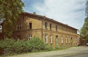 Am Markt (10): traufständiges Backsteingebäude mit umlaufendem Gesims: Straßenfront mit zwei Eingangstüren, in Oberschoss rechts Schlitzfenster: Giebelseite: hinten rechts Haus