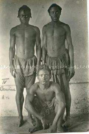 Gruppenbild dreier Männer der Bomome vor neutralem Hintergrund