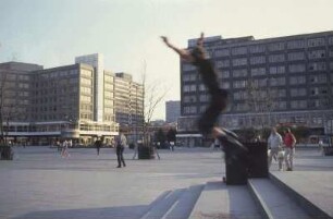 DDR. Berlin-Mitte. Alexanderplatz. Ansicht mit von einer Treppe springendem Rollerscater. Blick zur Weltzeituhr