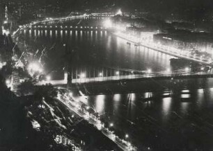 Budapest bei Nacht. Drei Brücken sind sichtbar (von vorn nach hinten: Elisabethbrücke, Széchenyi-Kettenbrücke und die Margaretenbrücke) sowie das Corso-Ufer mit den vielen Cafes