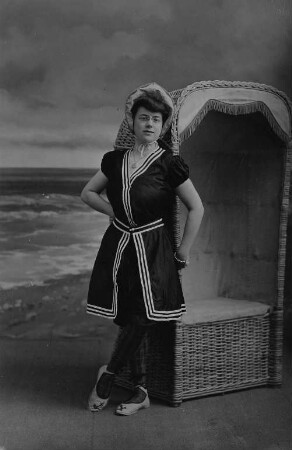 Frau in Badetracht vor Strandkorb