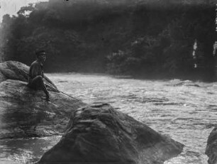 Angler : Ein Angler sitzt während des Fischens auf einem Felsen