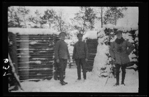3 Offiziere im Schnee vor Holzbauten