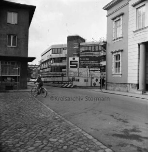 Kreissparkasse Stormarn: Hagenstraße: Zentrale: in Bau: mit Gerüst, Bauschild, Sparkassenemblem, Bauzaun: Fahrradfahrer: rechts Einmündung Weg zum Bürgerpark, Historisches Rathaus: links Einmündung Markt, Eckhaus Altbau Kreissparkasse: Straßenschilder, Verkehrsschilder
