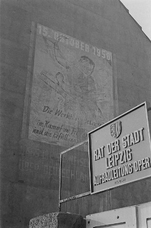 Blick auf eine Häuserfassade am Augustusplatz (damals Karl-Marx-Platz) in Leipzig mit einer Losung anlässlich der ersten Volkskammerwahlen am 15. Oktober 1950, im Vordergrund ein Schild mit der Aufschrift " Rat der Stadt Leipzig, Aufbauleitung Oper"