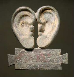 Ohrenvotiv mit griechischer Weihinschrift auf Tabula ansata: ΚΑΛΙ…CTH / ACCKΛΗΠΙ…/ EYXHN. An den Ohren Reste von Vergoldung