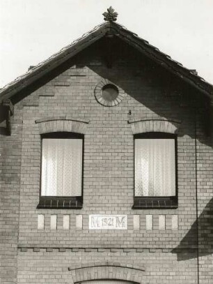 Schleife, Friedensstraße 5. Gehöft (1921). Wohnhaus. Giebel des Zwerchhauses mit Inschrift und Firstzier