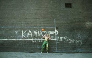 Aufnahme für die Reportagereihe „Außenseiter der Mode“: Studio Fong Leng, Amsterdam : Model in gelbem Top und grünen Pluderhosen nach Entwürfen von Fong Leng, mit einem Basketball und drei Jungs vor einer Graffitiwand