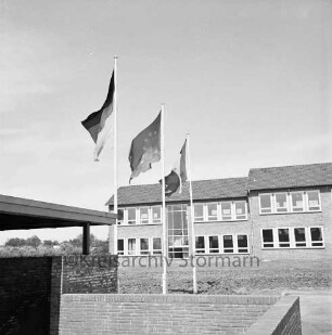 Verschwisterung mit Déville-lès-Rouen: Europafahne, Fahne der Bundesrepublik und Trikolore an den Fahnenmasten: im Hintergrund Emil-Nolde-Schule (Volksschule), 25. Mai 1969