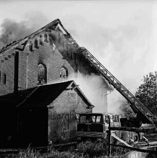 Gut Altfresenburg: Brand des Bullenstalls: Brandruine: Giebelfront mit Anbau: davor Löschfahrzeug mit Drehleiter, Rauchschwaden, Bäume: 24. August 1971